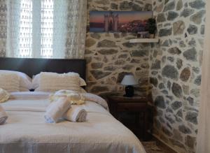 1 dormitorio con 1 cama con pared de piedra en Marios guesthouse Pelion, en Tsagkarada