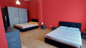 two beds in a room with red walls at Residence Il Vicoletto in Brolo
