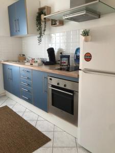 a kitchen with blue cabinets and a white refrigerator at Jeter l’ancre - studio in Calais