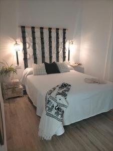 Un dormitorio con una gran cama blanca con una guitarra. en Ishel Trafalgar, en Zahora