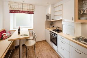 a kitchen with white cabinets and a table and chairs at Apartment Bellaria in Santa Cristina Gherdëina