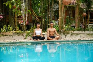 een man en vrouw die in meditatie zitten bij een zwembad bij Valley Village Phu Quoc in Phu Quoc