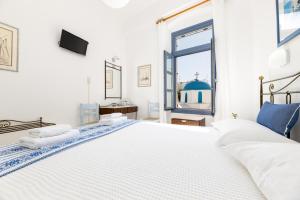 a white bedroom with a large bed and a window at Hotel Dina in Parikia