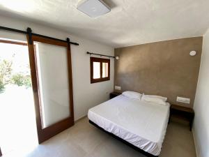um quarto com uma cama branca e uma janela em Agradable casa rural en zona reserva natural. em Sant Francesc Xavier