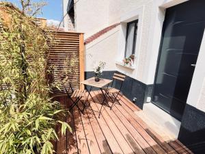 una terraza de madera con mesa y sillas. en Duplex standing 7min➤Fontainebleau-INSEAD⎮45min➤Paris en Veneux-les-Sablons
