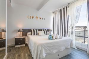 a white bedroom with a bed and a large window at Apartments Vistas Mar Bahia in Cádiz