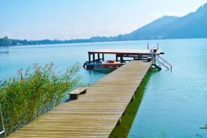 un muelle en un lago con un barco en el agua en Haus am See en Sankt Kanzian