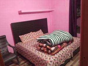 a pink bedroom with a bed with a pillow and a chair at Badri Kedar Hometay in Joshīmath