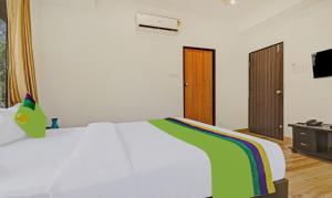 Treebo Trend Villa Inn Aurangabad في أورانغاباد: غرفة نوم بسرير ابيض وتلفزيون