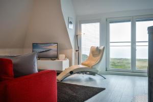 a living room with a red chair and a television at Westcoast in Hörnum