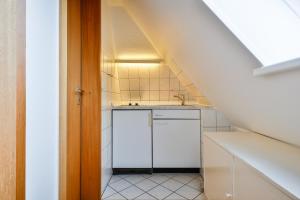 a small white kitchen with a sink and a staircase at Westcoast in Hörnum +34 photos