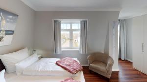 - une chambre avec un lit, une chaise et une fenêtre dans l'établissement Sylter Meeresbrise, à Wenningstedt