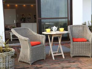 two wicker chairs and a white table with two chairs at Sylt Cottage in Morsum