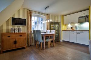 uma cozinha com mesa e cadeiras e uma cozinha com armários brancos em Duenenperle em Rantum
