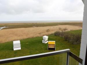 three chairs sitting on the grass on a balcony at Fernsicht in Morsum