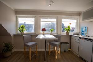 a kitchen with a table and two chairs and windows at Sylt Like in Tinnum +2 photos