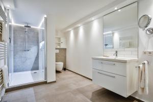La salle de bains blanche est pourvue d'une douche et d'un lavabo. dans l'établissement Lornsenduene, à Westerland