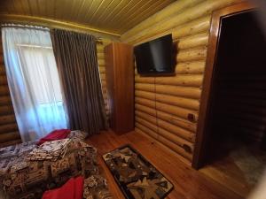 1 dormitorio con 1 cama y TV en la pared en Садиба У Марії, en Polyana