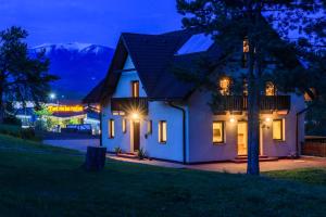 una casa de noche con montañas en el fondo en Apartmány Ráztoky, en Liptovský Mikuláš