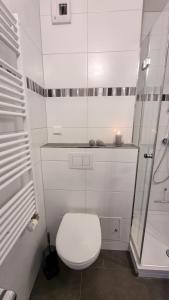 La salle de bains blanche est pourvue d'une douche et de toilettes. dans l'établissement Ferienpark F12-004 Ferienpark, à Heiligenhafen