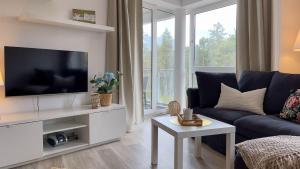 ein Wohnzimmer mit einem blauen Sofa und einem TV in der Unterkunft Strandhaus Nordseebrandung Fewo A3.3 in Cuxhaven