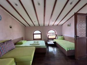 a room with two beds and a couch and windows at BRUNETTE BEAUTIES Guesthouse & Studio Sinemorets in Sinemorets