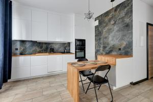 a kitchen with white cabinets and a wooden table and chairs at Lion Apartments - Botanica in Gdańsk