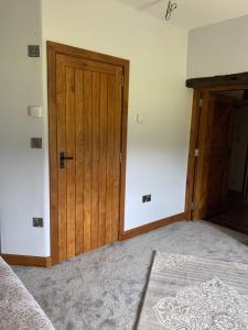 an empty room with a wooden door and a bed at Gooseford Farm in Okehampton