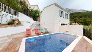 a swimming pool with two chairs and a house at Gemütliche Villa mit Pool in Brela