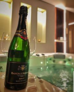 a bottle of champagne sitting on a table next to a bathtub at Spa Pleasure Apartman in Novi Sad