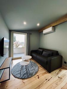un soggiorno con divano nero e tavolo di LOFT et SPA sous les étoiles a Foix