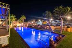 uma piscina à noite com palmeiras e luzes em Vila Origens Boutique Hotel Albufeira – Adults Only em Albufeira