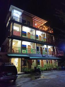 ein Gebäude mit Balkon und ein Auto auf einem Parkplatz in der Unterkunft Pamujo Hostel in Baclayon