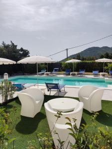 basen z białymi krzesłami i stołami oraz basen w obiekcie Natur Hotel Tanca w mieście Cardedu