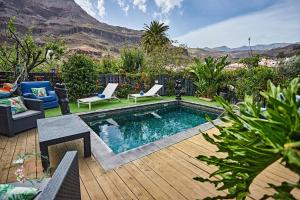 a swimming pool with two chairs and a table at Finca OASIS Fataga in Maspalomas