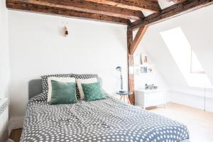 a white bedroom with a bed with green pillows at La Petite Cathédrale Strasbourg séjour de 30 jours ou plus in Strasbourg