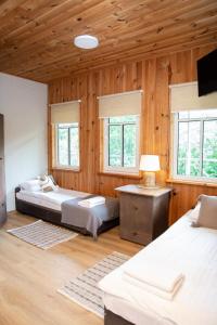 two beds in a room with wooden walls and windows at Mėlynojo karpio barža in Kintai