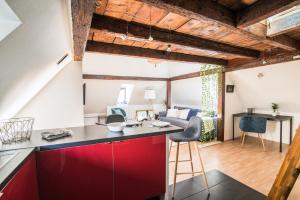 a kitchen with red cabinets and a living room with a couch at La Petite Cathédrale Strasbourg séjour de 30 jours ou plus in Strasbourg