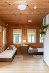 two beds in a room with wooden walls and windows at Mėlynojo karpio barža in Kintai