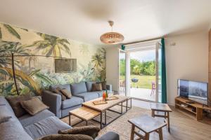 a living room with a couch and a tv at Green Lodge - Piscine chauffée et grand Jardin à proximité des Plages de Pléneuf Val-André in Saint-Alban