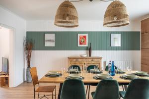 a dining room with a wooden table and chairs at Green Lodge - Piscine chauffée et grand Jardin à proximité des Plages de Pléneuf Val-André in Saint-Alban
