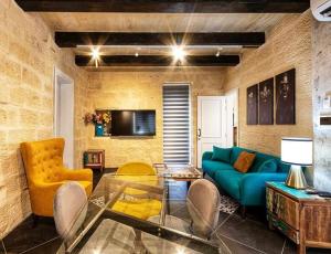 salon z niebieską kanapą i żółtymi krzesłami w obiekcie Nigret Step’n’Suites w mieście Żurrieq