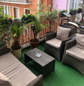 eine Terrasse mit Stühlen, einem Tisch und Pflanzen in der Unterkunft Hôtel Poussin in Paris
