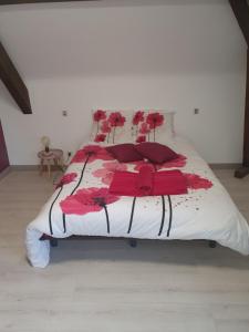 a bed with a red and white comforter on it at Le Curieux de Conques in Saint-Cyprien-sur-Dourdou