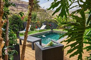 a swimming pool with a table and chairs in a garden at Fataga finca private with pool in Maspalomas