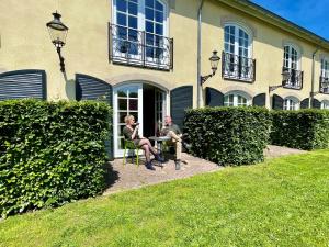 two people sitting at a table in front of a building at Hotel & Restaurant - Auberge De Hilver in Diessen