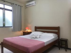 a bedroom with a bed with a pink blanket and a window at Regina Del Mare Residence Apartamentos completos para até 05 pessoas a 50 metros da praia in Florianópolis