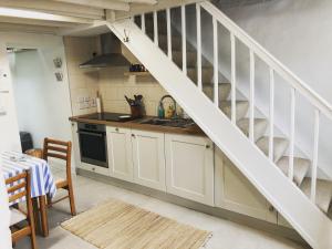a kitchen with white cabinets and a spiral staircase at Bluebell Cottage in Kilmore Quay