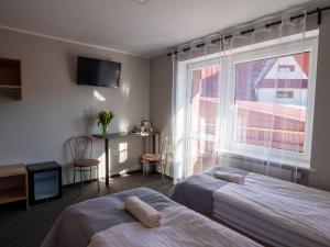 ein Hotelzimmer mit 2 Betten und einem Fenster in der Unterkunft Ada in Muszyna