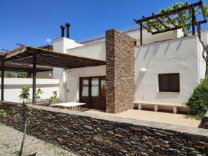 Casa blanca con pared de piedra en El Domingo en el Valle, en Fondón